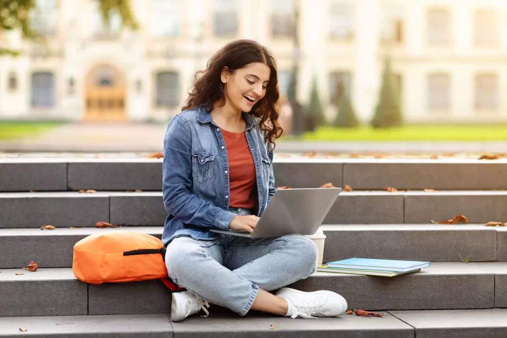 Studente universitario che valuta un prestito per sostenere tasse, affitto e spese di studio, con libri e pc sul tavolo.
