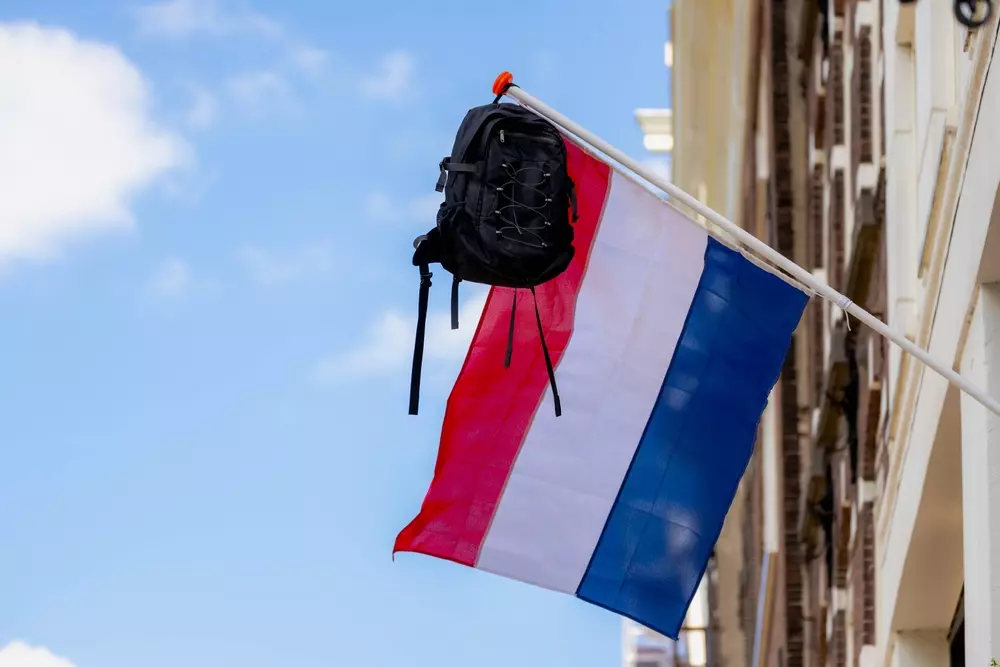 studente Erasmus con zaino appeso alla bandiera dei Paesi Bassi in una città universitaria olandese
