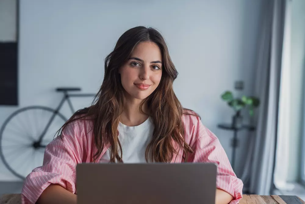 Studente che segue un corso universitario online da casa con laptop e appunti
